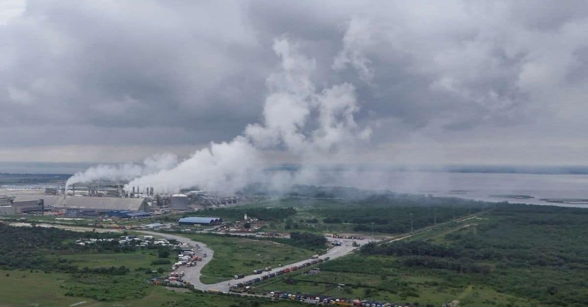 Industrial area with refinery emissions and smoke clouds in the background.