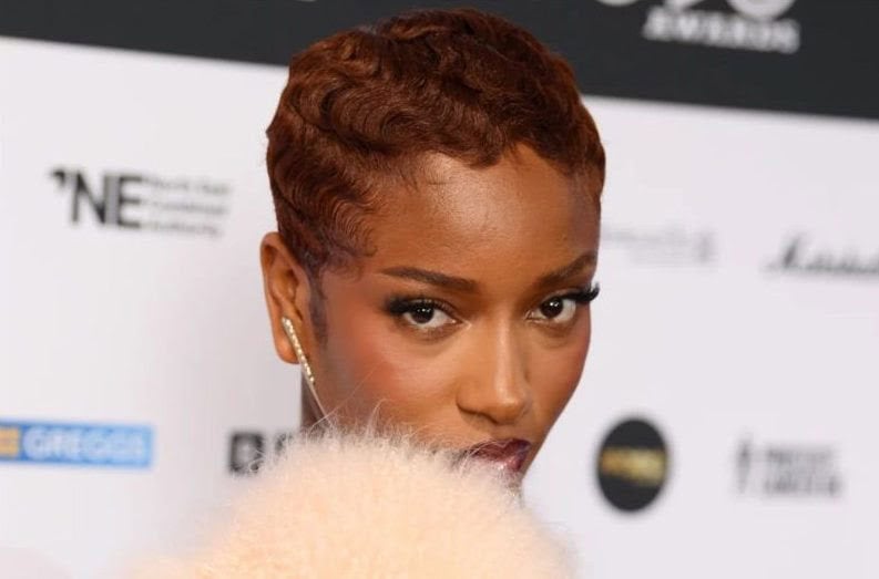 A close-up of a confident African woman with short, curly hair at a music awards event.
