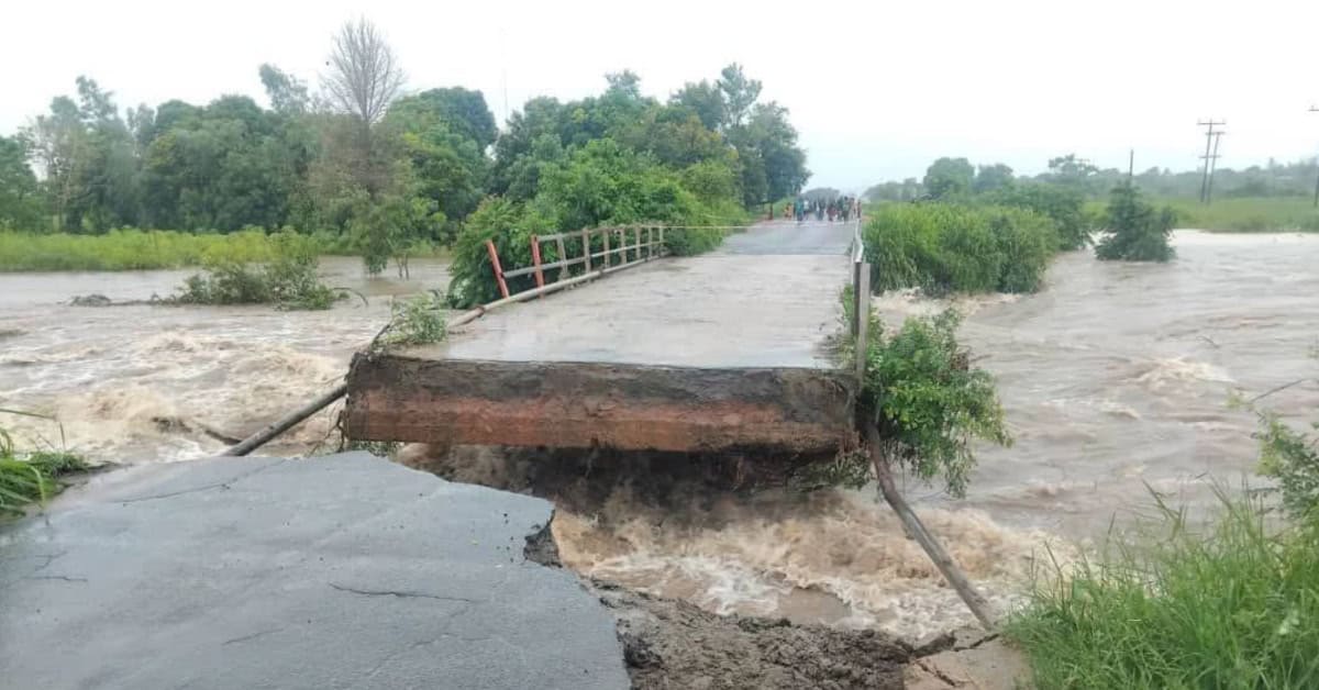 Flooded bridge with collapsing section due to rapid floodwaters.