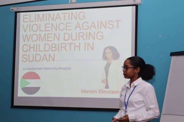 Woman presenting on eliminating violence against women during childbirth in Sudan.