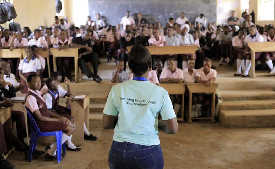 Isaac Mwebazemukama Transforms Sustainability and Youth Empowerment in Uganda 1 Teacher addressing students in a Ugandan classroom promoting education and youth empowerment.