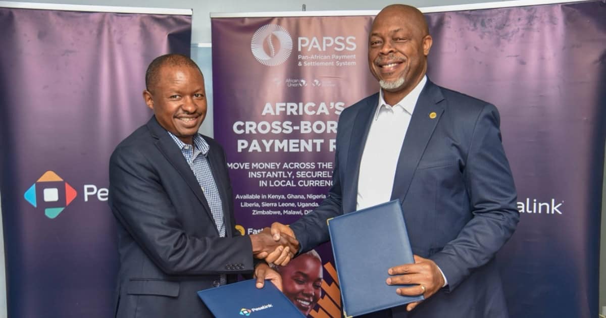 Two men shaking hands at a payment conference with PESALINK and PAPSS banners.