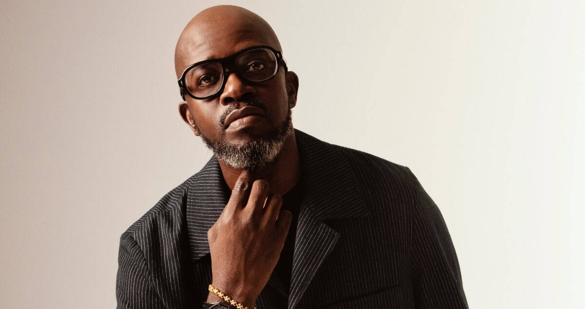 Portrait of a Black male artist in Lagos, Nigeria, with glasses and stylish attire.