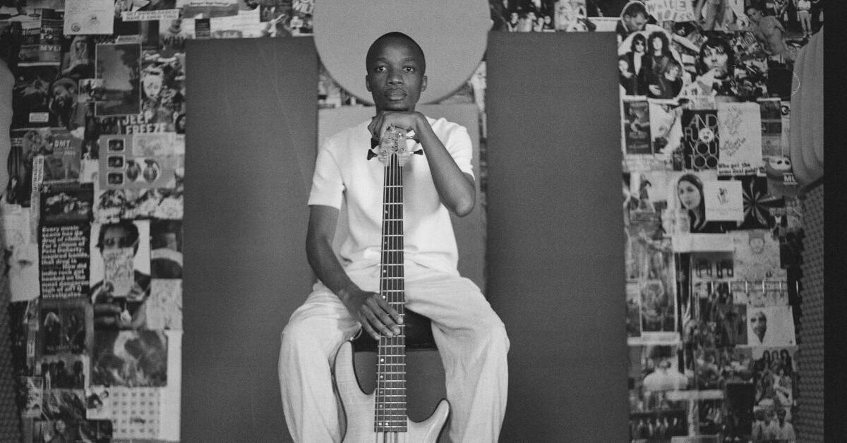 Young boy holding guitar in Cape Town street, celebrating jazz revival.