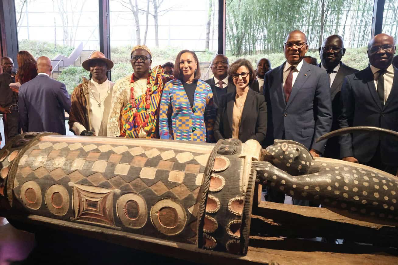 Ivorian officials and cultural leaders with the sacred talking drum in a museum setting.
