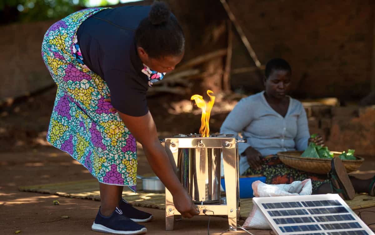 Woman using clean cooking stove in Zambia for sustainable energy.