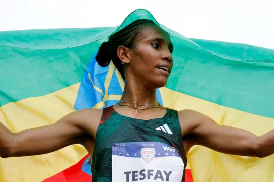 Ethiopian marathon runner Fotyen Tesfay with Ethiopia flag after race.