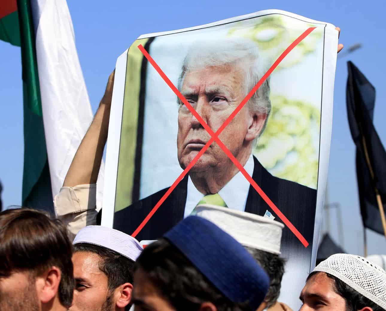 Protesters hold a sign with Donald Trump's image crossed out during a demonstration.