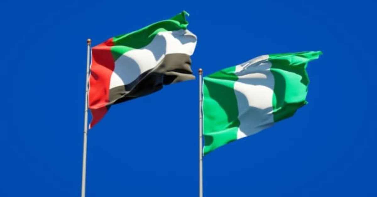 Flags of UAE and Nigeria flying together against a clear blue sky.