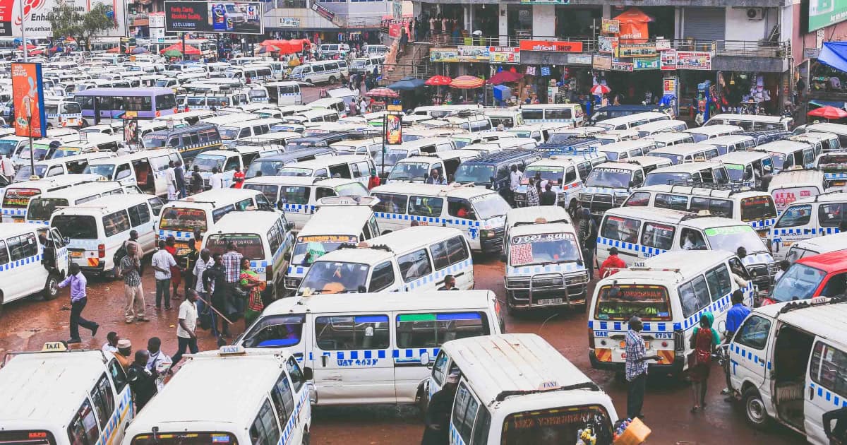Crowded minibus station with numerous vehicles and pedestrians.