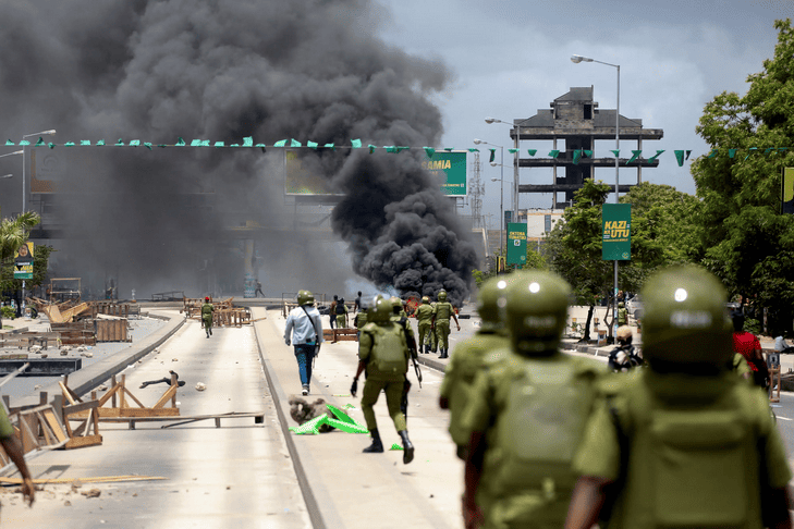 Security forces and protesters amid smoke after election crackdown in Tanzania.