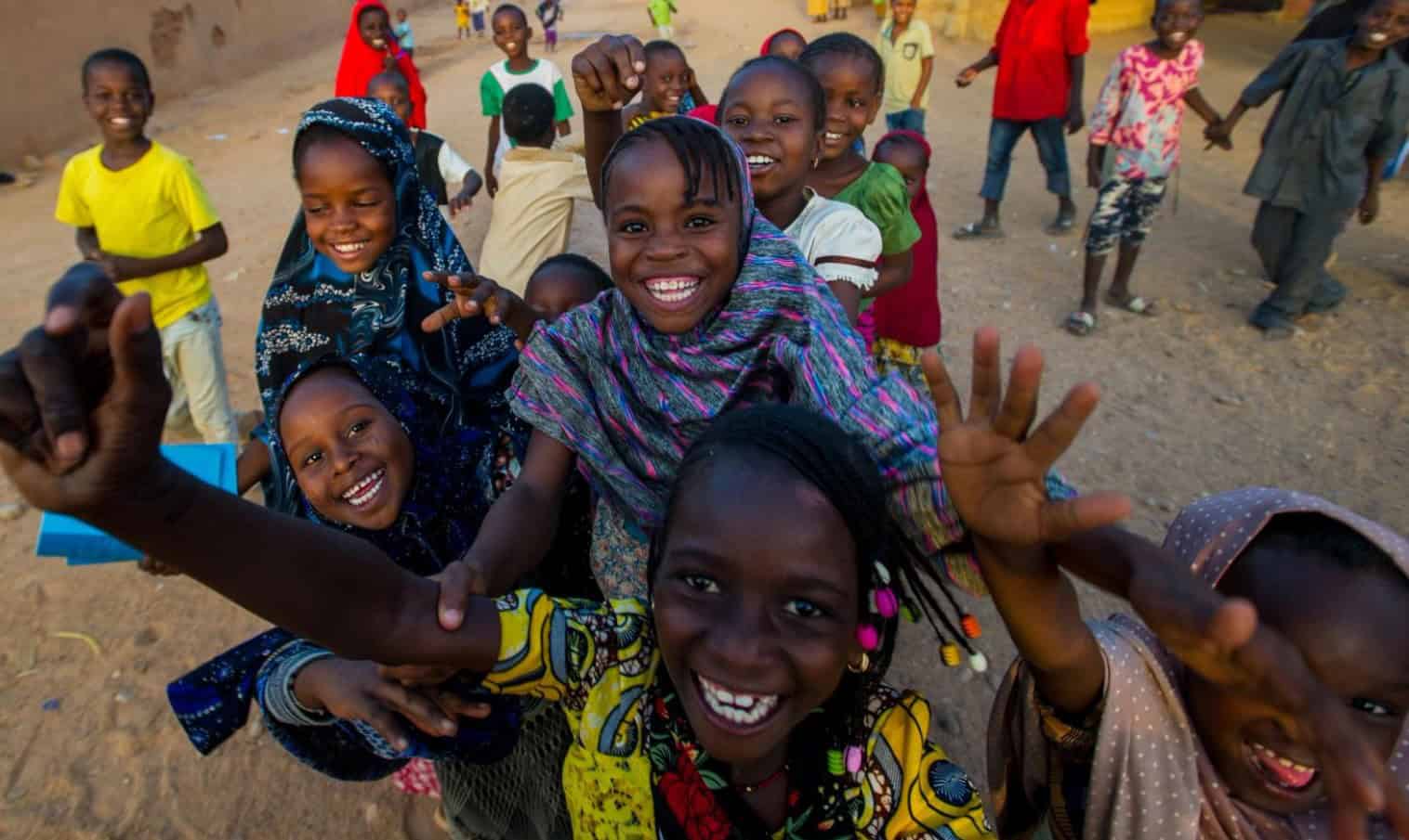 Happy African children smiling and playing together in an outdoor setting.