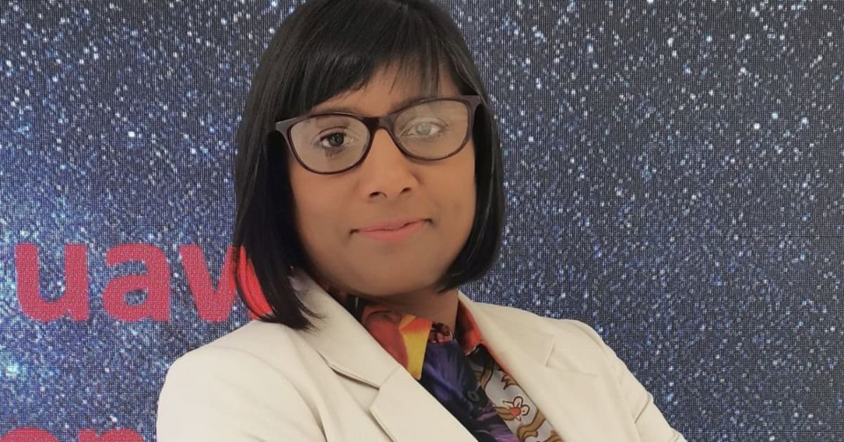 Woman with glasses in front of a starry background, promoting digital growth and language diversity.