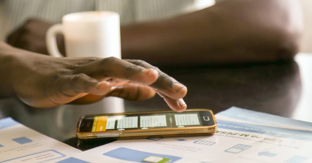Person using mobile payment app on smartphone in Africa, digital economy growth.