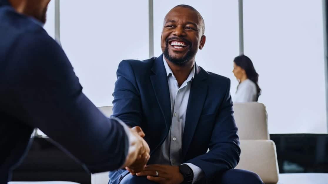 Business professionals shaking hands in a modern office setting in Africa.