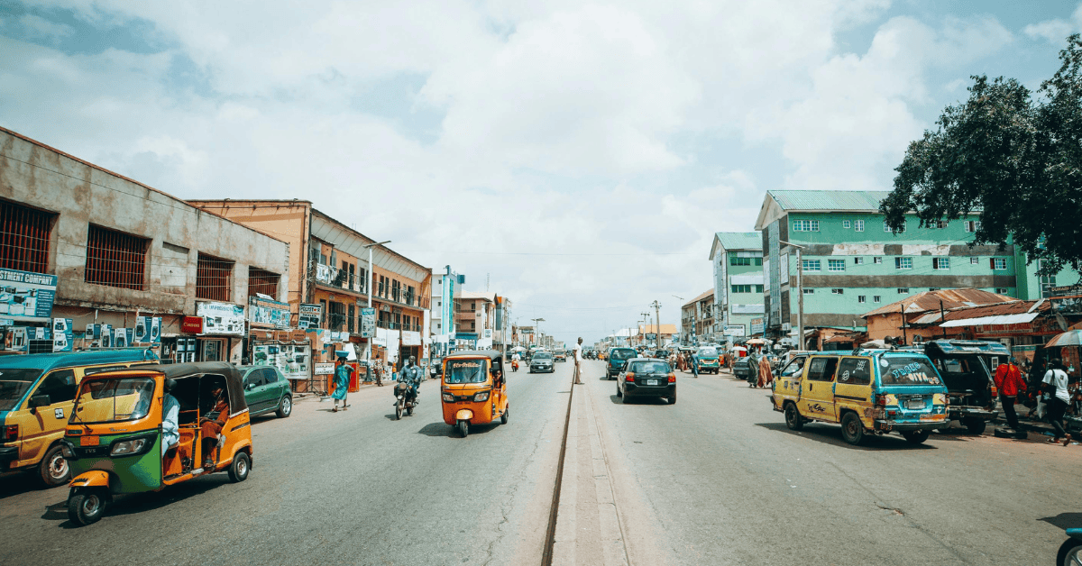 Urban street scene in Liberia with vehicles, shops, and pedestrians.