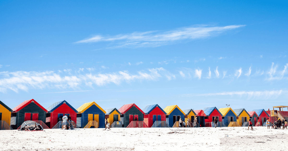 Colorful beach huts line the sandy coast, attracting visitors to Africa's scenic seaside resorts.