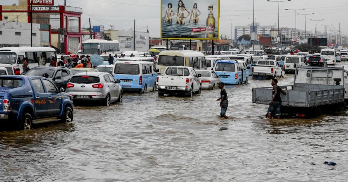 Urban street flooding in Angola with vehicles and pedestrians affected by heavy rains.