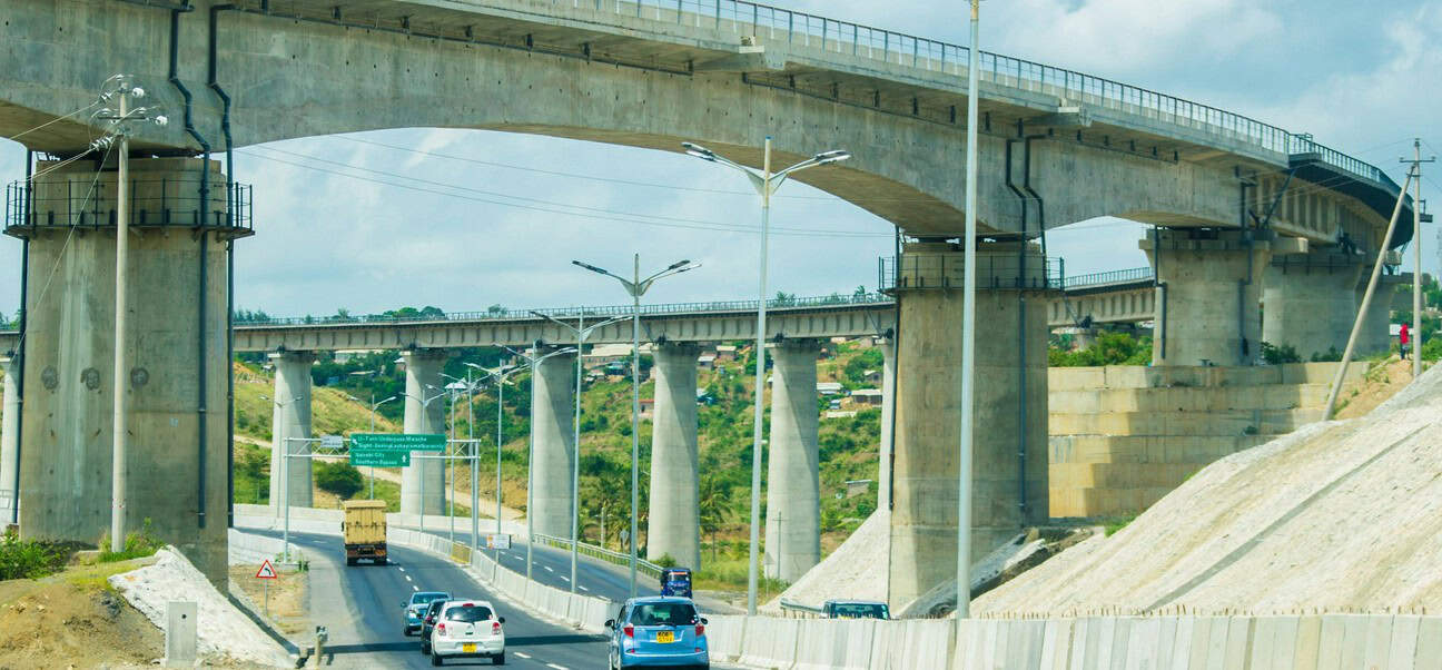 Highway overpass with multiple lanes and supporting pillars in a cityscape.