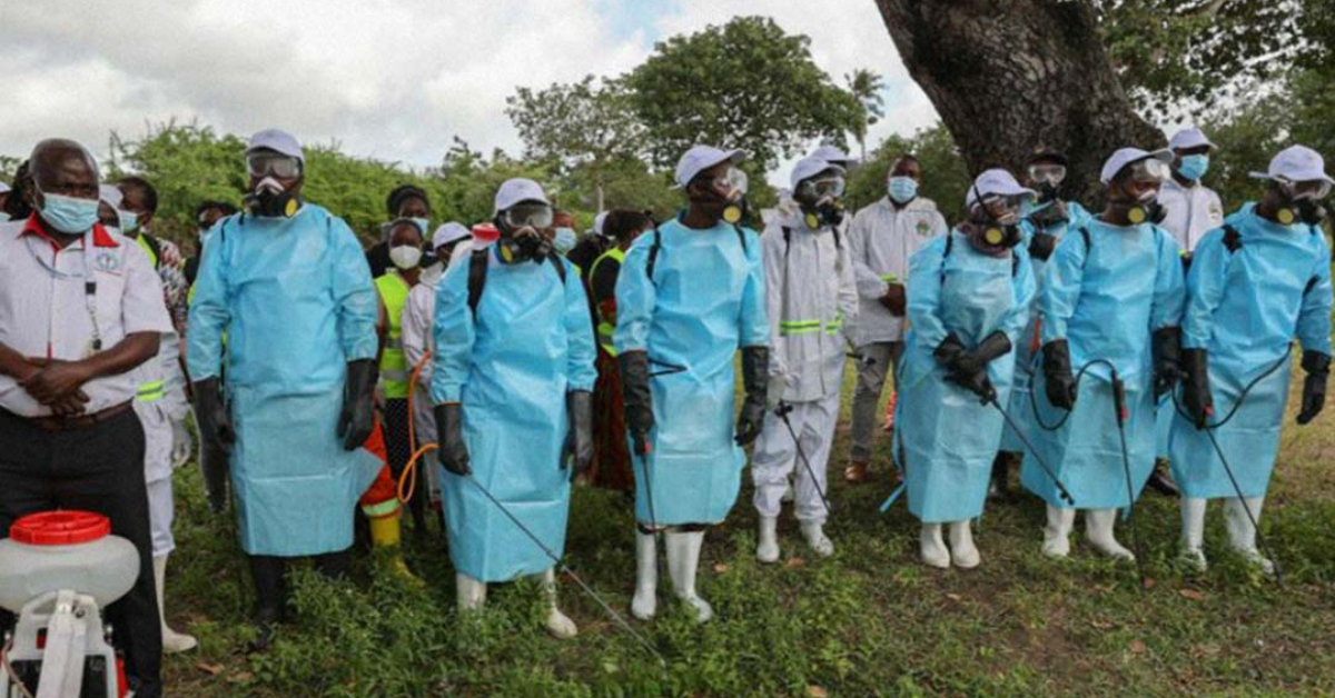 Healthcare workers in protective gear conducting malaria prevention efforts outdoors.