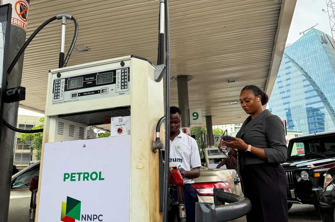 Petrol station with two women filling up and checking their phones at a fuel pump in an urban settin.