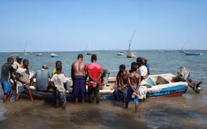 Fishermen gather near boats on Mozambique coast amid maritime tensions.