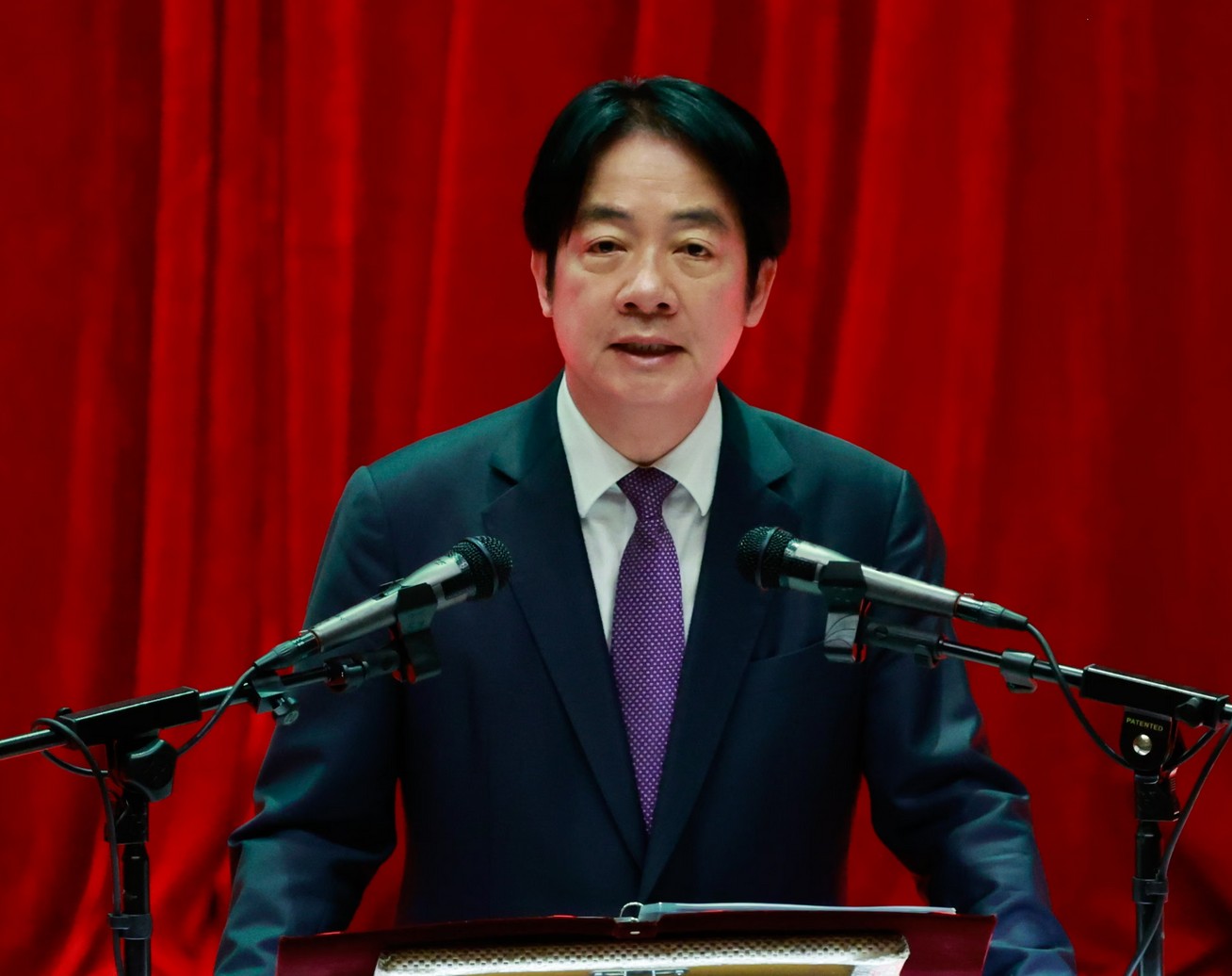 African leader delivering speech at a formal event with microphones.