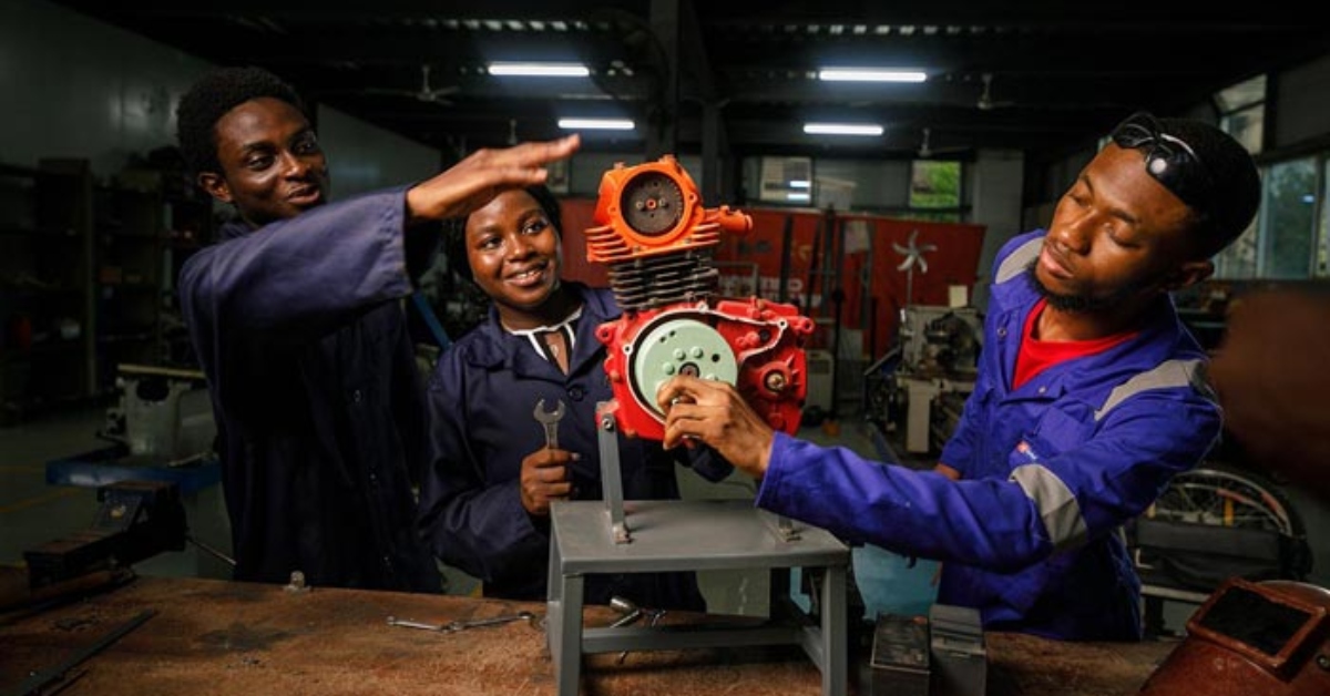 Engineering students working on a mechanical project in a workshop.