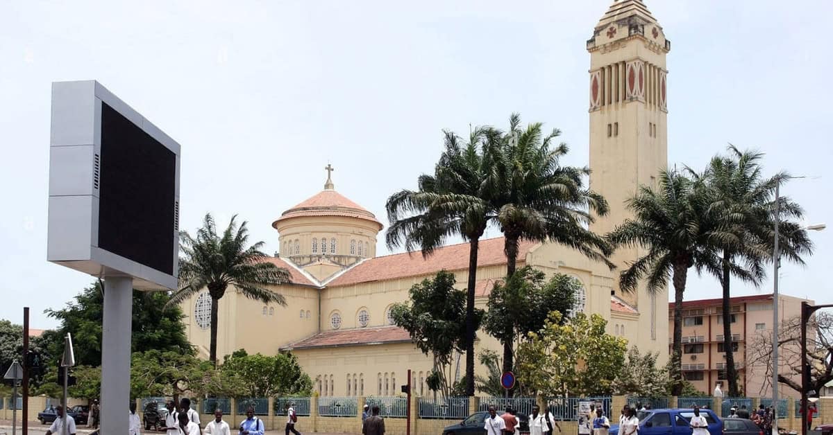 Historic Ethiopian church with a tall clock tower in Addis Ababa, surrounded by palm trees.