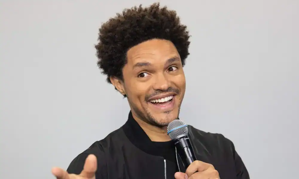 Trevor Noah delivering a speech with a microphone, engaging the audience.