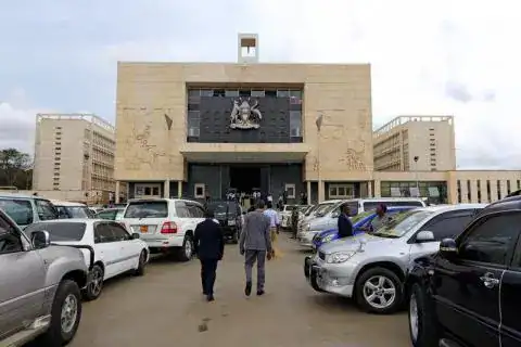 Uganda Parliament building with cars and people outside, symbolizing governance.