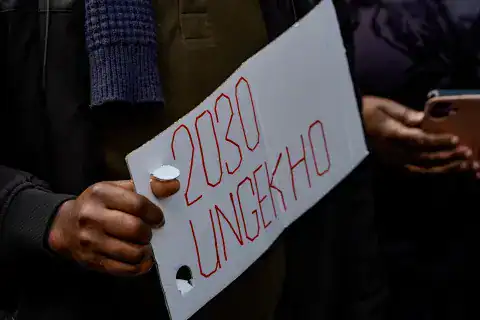 Protester holding a sign that reads "OBO UNLOCKHO" during Zimbabwe student protests.