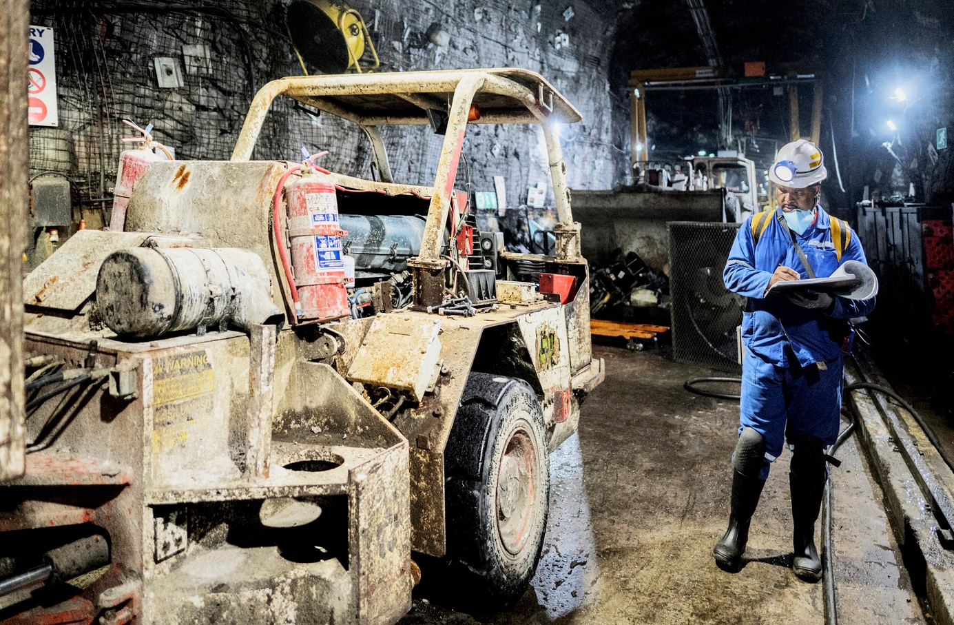 Mining machinery and worker in an underground mining operation.