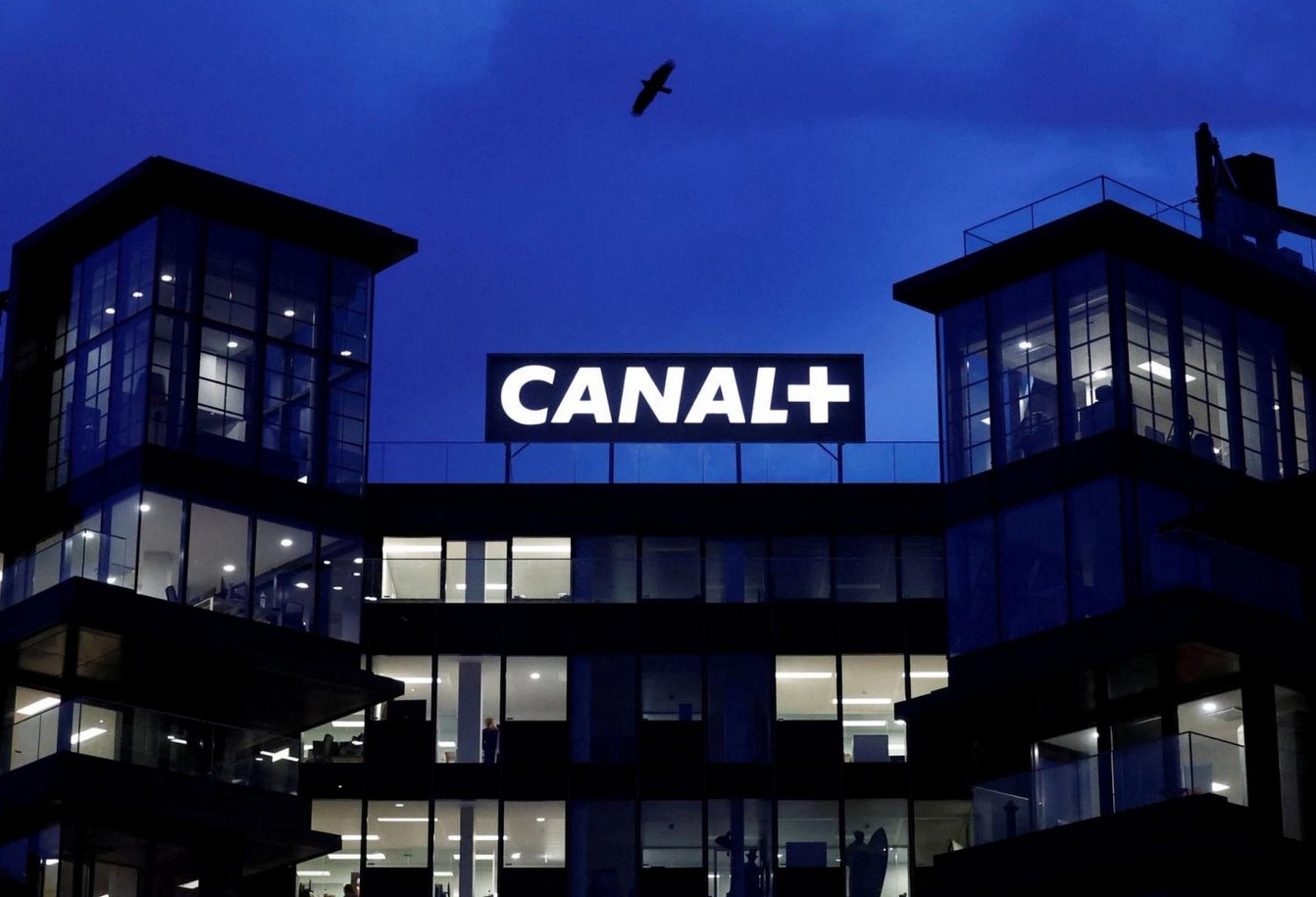 Modern Canal+ office building illuminated at night with logo visible.