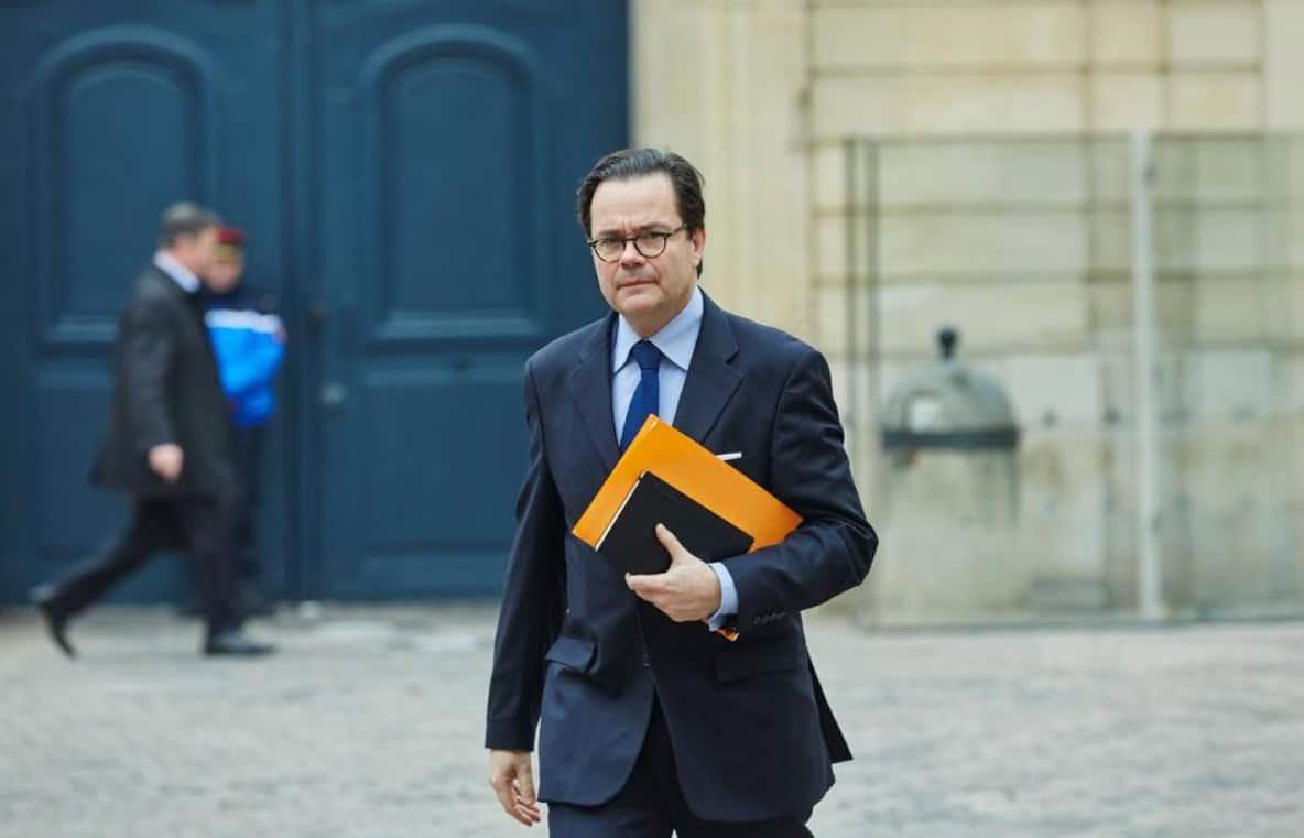 Business professional in formal attire holding folders near a historic building.