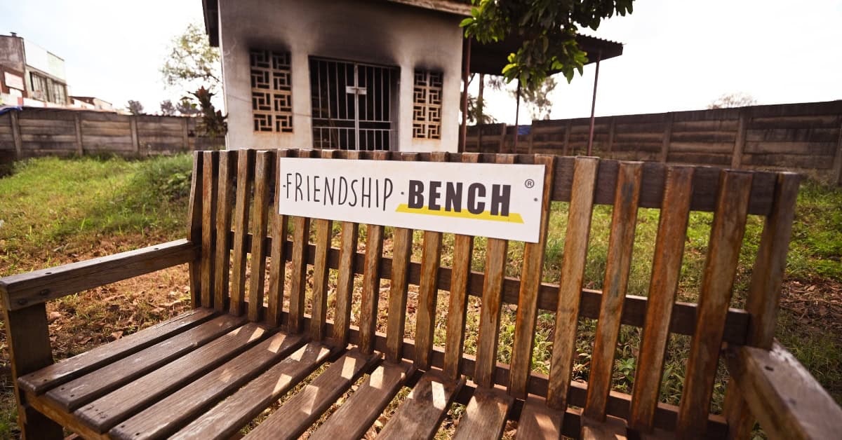 Community bench with "Friendship" sign in Zimbabwe, symbolizing mental health support.