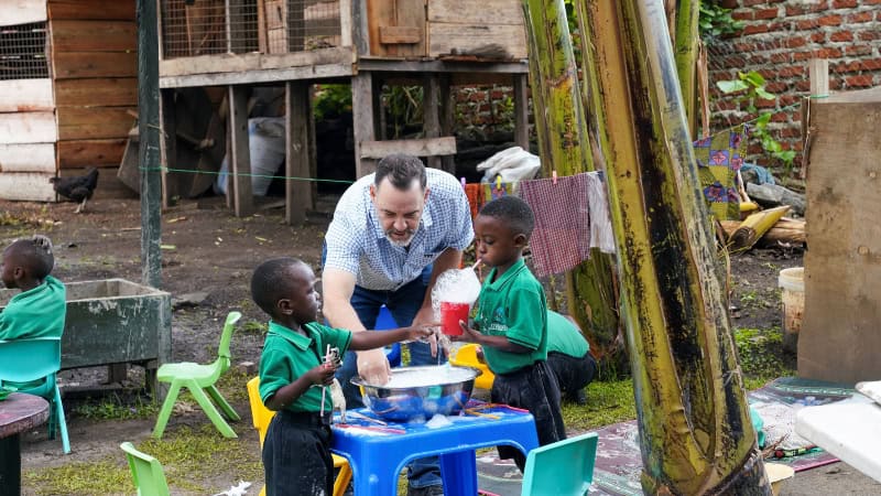 Man engaging with children at a community water activity in Africa.