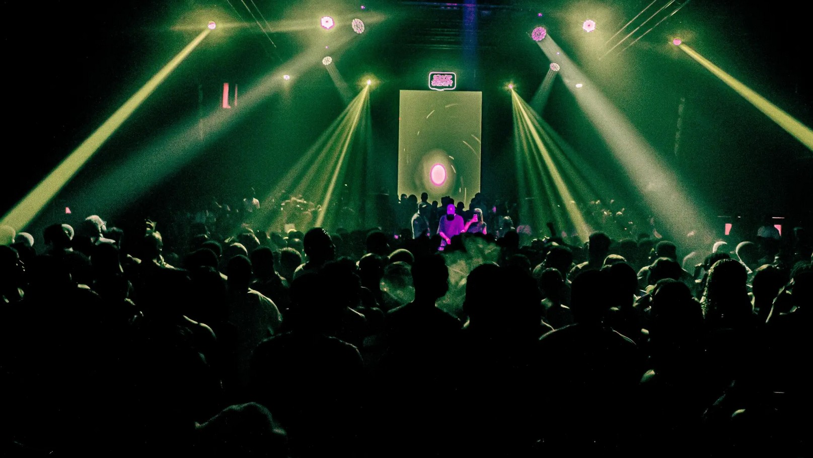 Crowd enjoying a lively Lagos rave with colorful lights and energetic atmosphere.