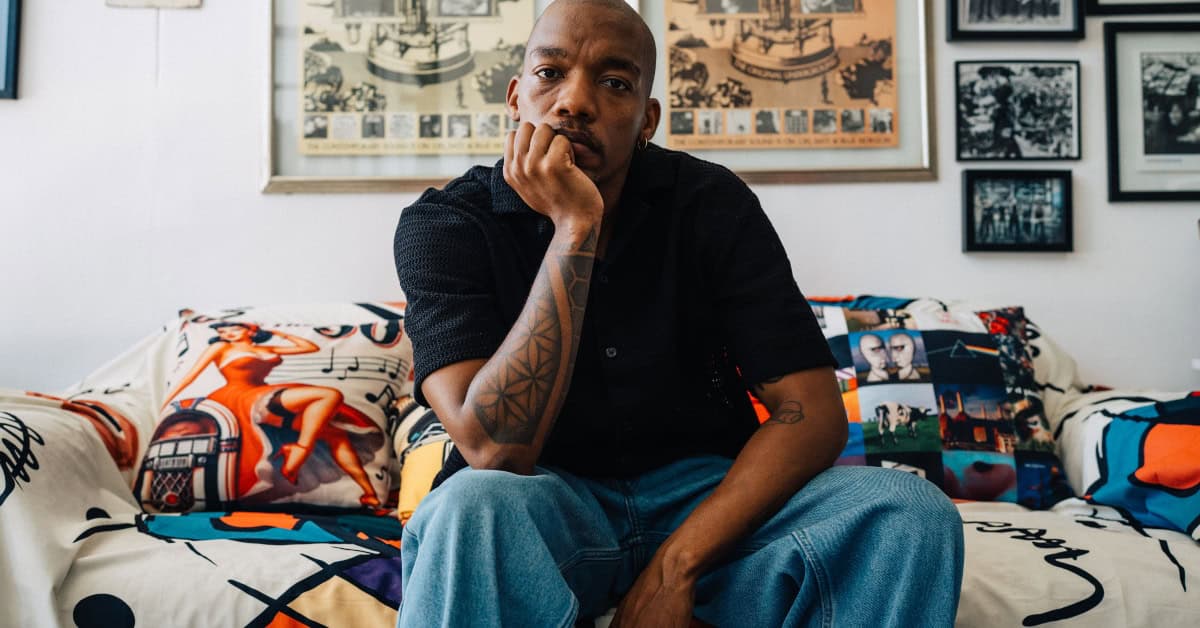 African artist Muzi in a thoughtful pose on a decorated sofa.
