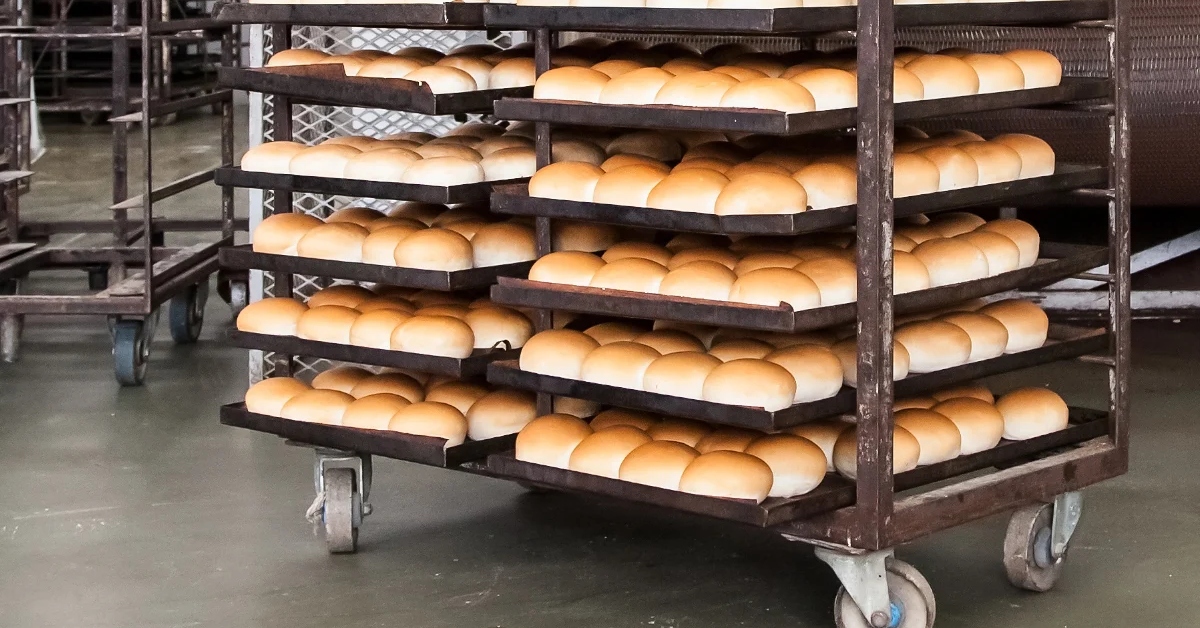 Bread racks with loaves of bread in a bakery setting.