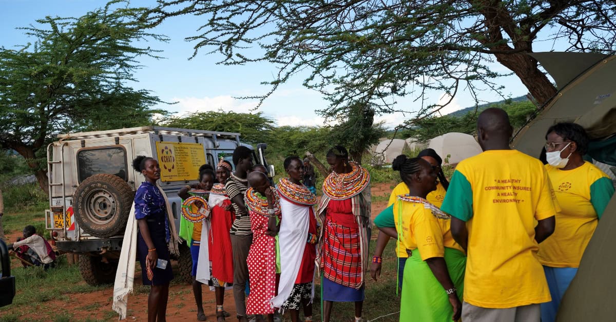 Community members gather around health workers in Kenya.