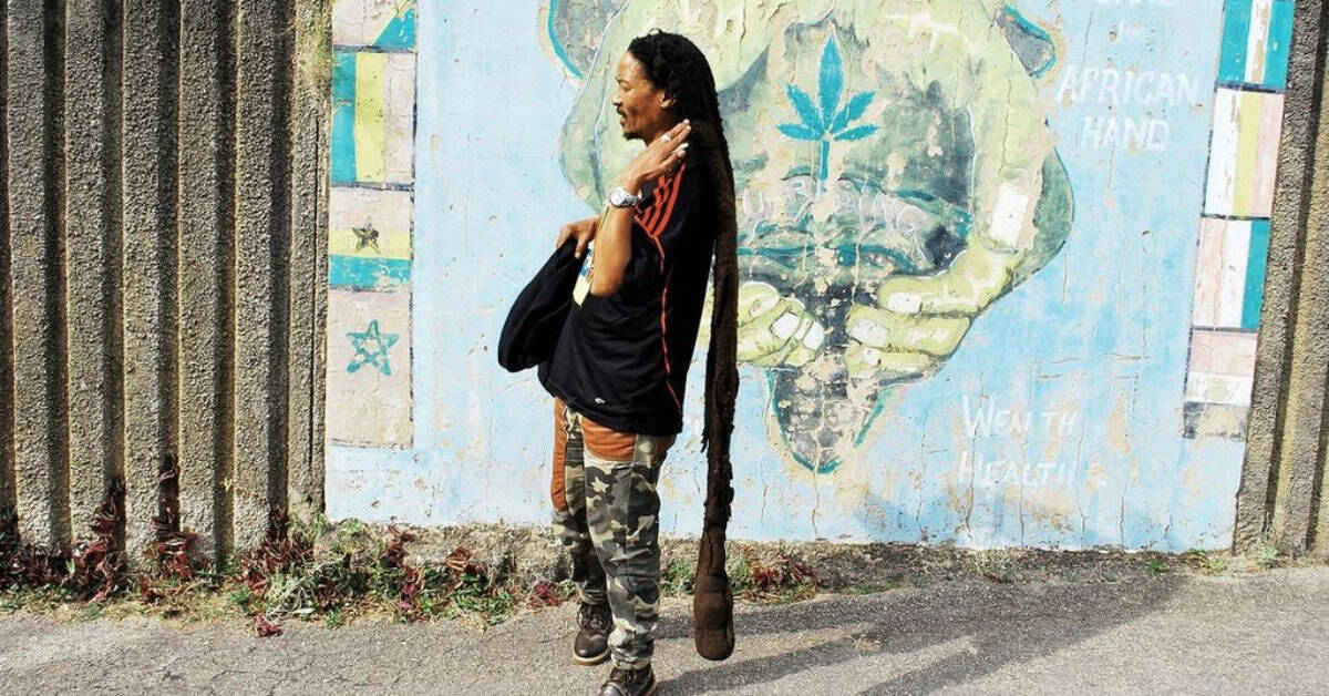 African woman standing near colorful mural wall.