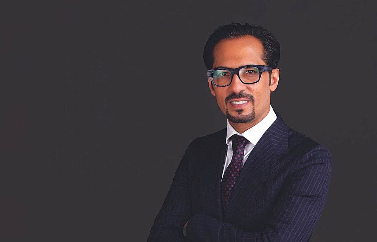 Business professional in formal suit and glasses smiling confidently.