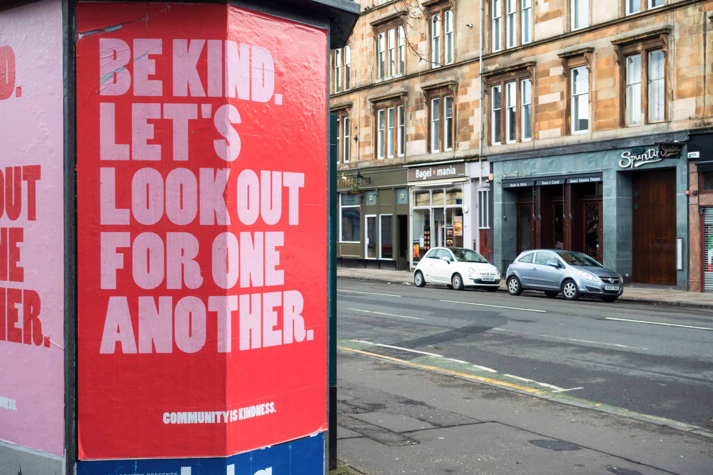Street poster message, "Be Kind. Let's Look Out for One Another."