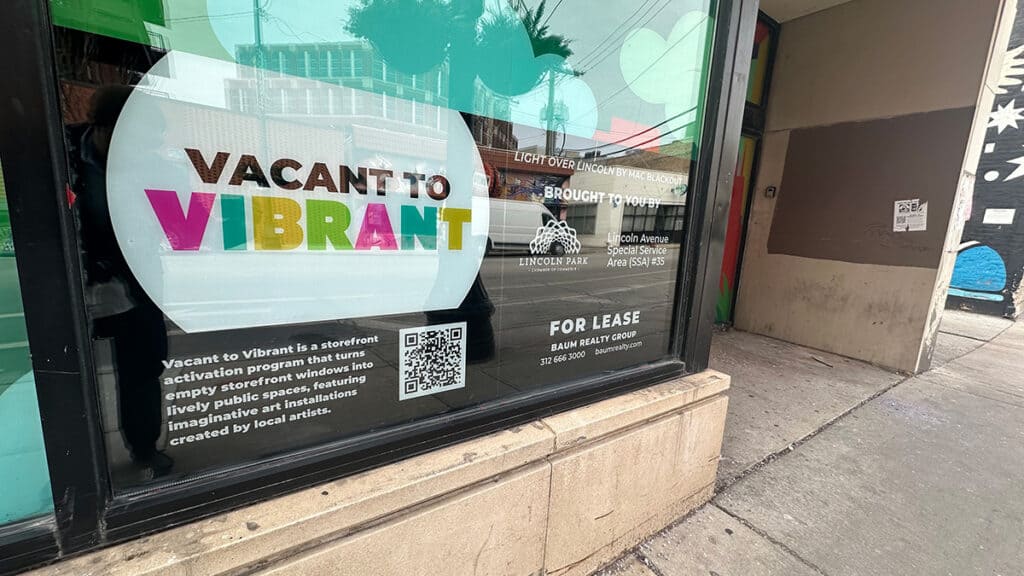 Close up of Vacant to Vibrant signage installed in windows of storefront in Lincoln Park, Chicago.