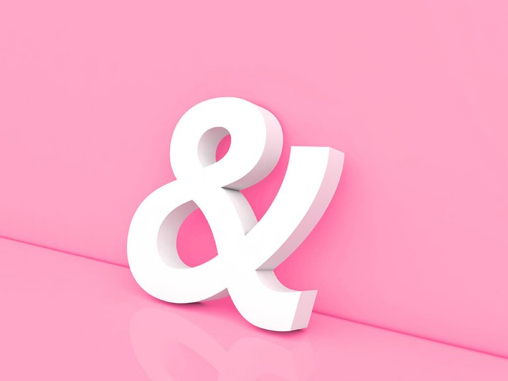 Sculptural ampersand leaning against a pink wall.