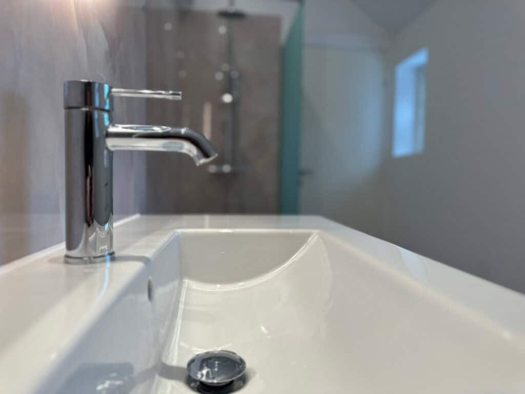 Nærbillede af krom armatur og hvidt badekar i nyrenoveret badeværelse
