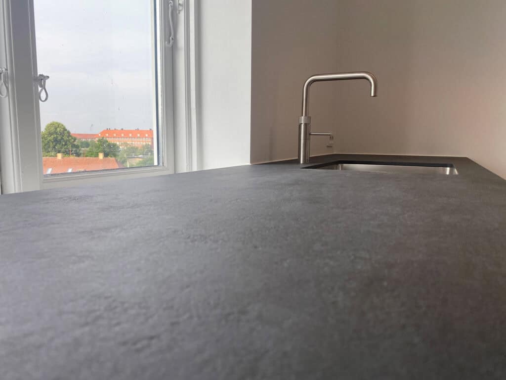 Køkkenbordplade i mørkegråt materiale set fra siden ved vindue