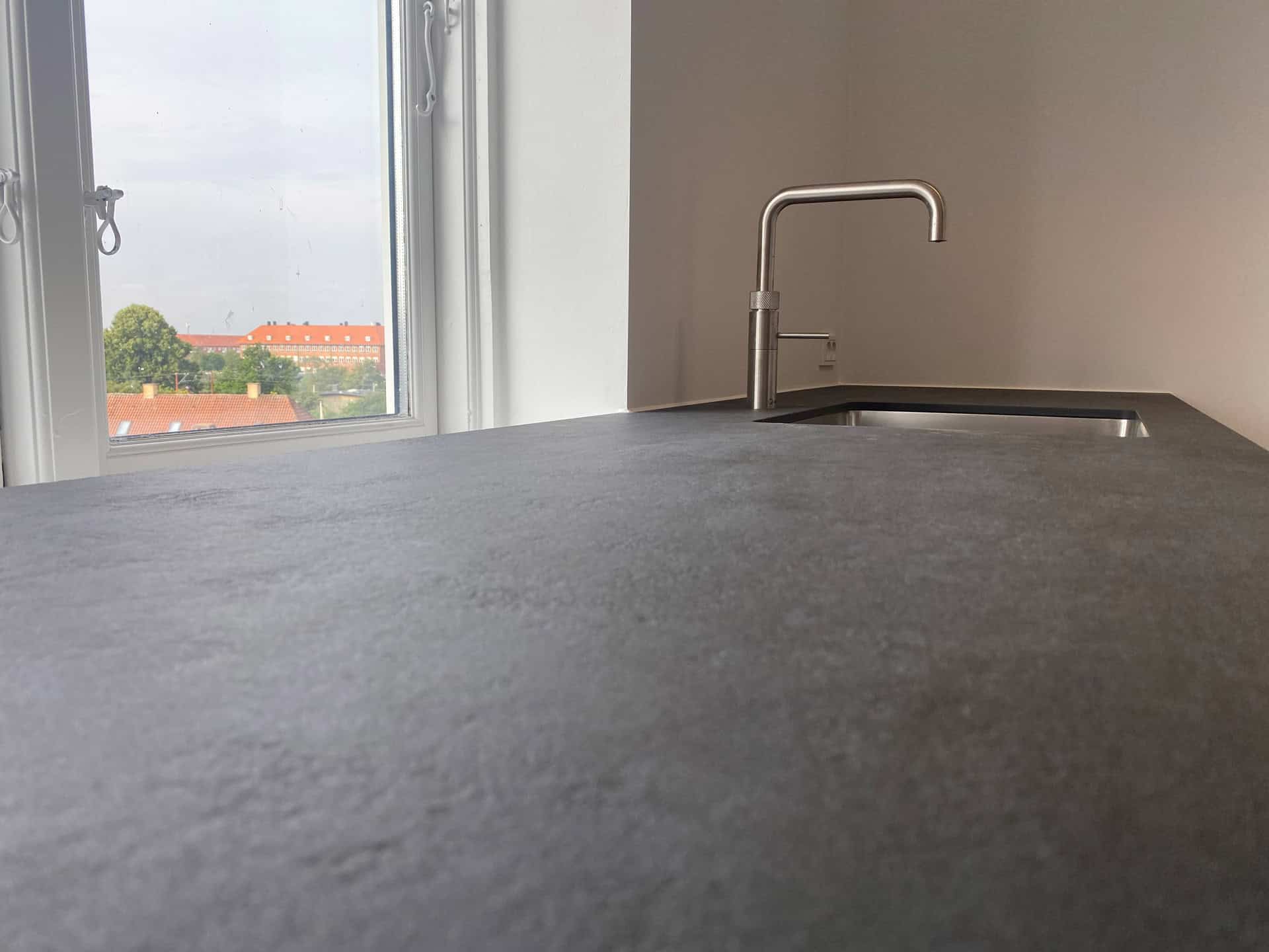 Køkkenbordplade i mørkegråt materiale set fra siden ved vindue