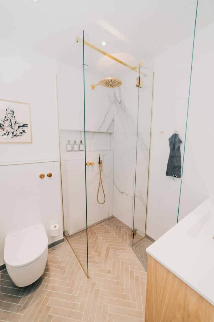 hvidt badeværelse med detaljer i guld og træ